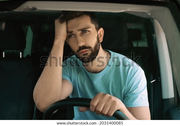 Stressed man in driver\'s seat of modern car,\
view through\
windshield