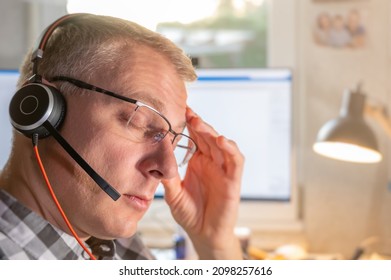 Stressed Man With Headache In Home Office With Headset