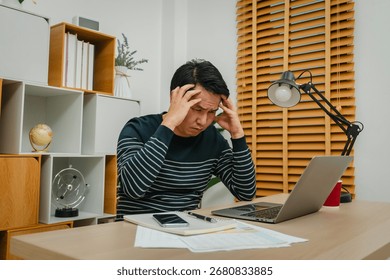 stressed man headache while working with a laptop computer at home office