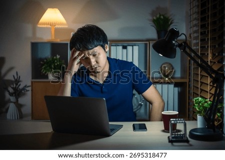 stressed man headache while working with laptop at a night