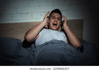 stressed man with panic attacks screaming while having nightmare at night