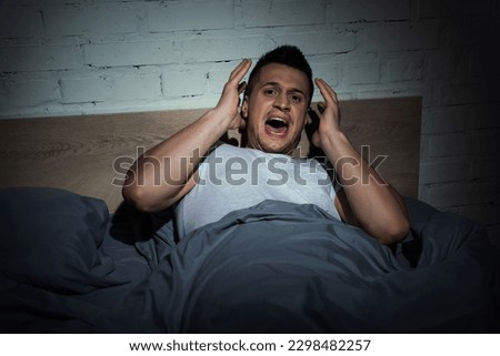 stressed man with panic attacks screaming while having nightmare at night
