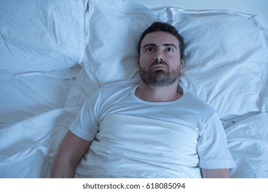 Stressed Man Trying To Sleep In His Bed At Night