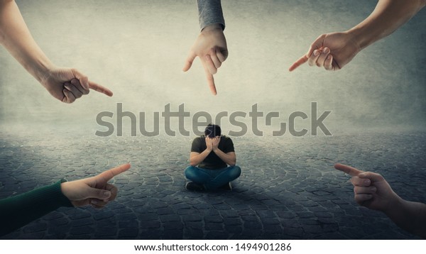 Stressed man, under pressure, sitting on floor\
cover face feel discomfort as a lot of hands pointing forefingers\
to him blaming as guilty. Human depression, social anxiety, victim\
of mental distress.