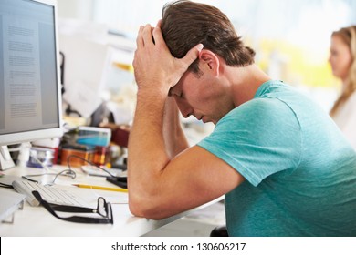 Stressed Man Working At Desk In Busy Creative Office - Powered by Shutterstock