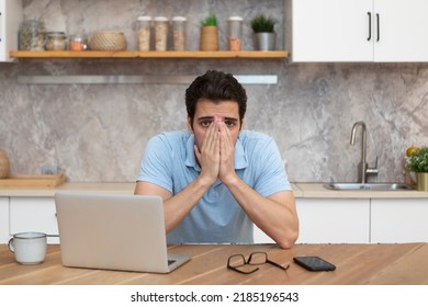 Stressed Man Working On Laptop In The Kitchen At Home. Distance Work Concept