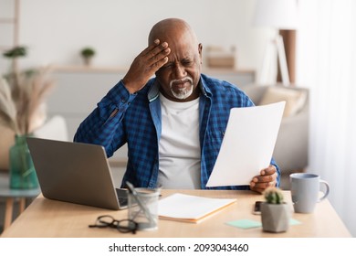 Stressed Mature African American Businessman Holding Paper Reading Bills Or Tax Form Having Financial Problem With Bank Documentation Sitting In Modern Office. Business Issue Concept - Powered by Shutterstock