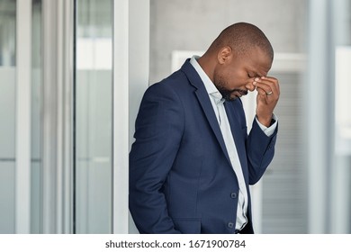 Stressed mature business man rubbing eyes in office. African american businessman in formal feeling tired for fatigue and headache. Depressed and anxious man in office feeling frustrated after layoff.