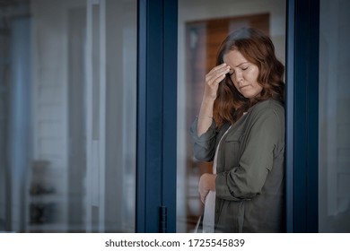 Stressed Mature Woman Standing Near Window Suffering From Strong Headache. Middle Aged Redhead Woman With Terrible Migraine Holding Head With Closed Eyes. Mid Lady Feels Pain In Stomach, Copy Space.