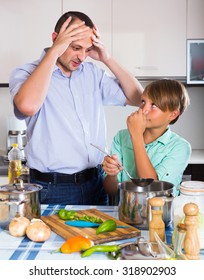 Stressed Middle Age Man And Son Cooking Together At Kitchen