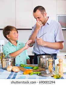 Stressed Middle Age Man And Young Son Cooking Together At Kitchen