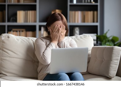 Stressed Middle Aged Woman Hiding Face With Both Hands. Depressed Senior Older Grandmother Crying After Reading Bad News Message On Laptop. Unhappy Mature Elderly Lady Feeling Desperate Alone At Home.