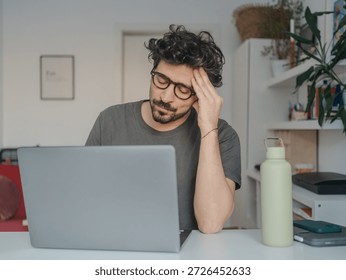Stressed middle eastern looking young man working on laptop at home, work and mental fatigue concept