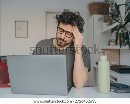 Stressed middle eastern looking young man working on laptop at home, work and mental fatigue concept