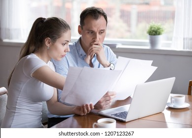 Stressed Millennial Married Couple Sitting At The Desk At Home Use Laptop Checking Documents Unpaid Bills, Taxes, Due Debt, Bank Account Balance. Bankruptcy Lack Of Money Financial Problems Concept