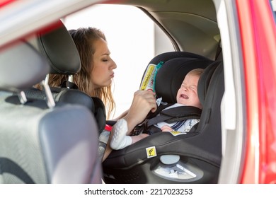 Stressed Mother With Her Crying Baby In The Back Of The Family Car