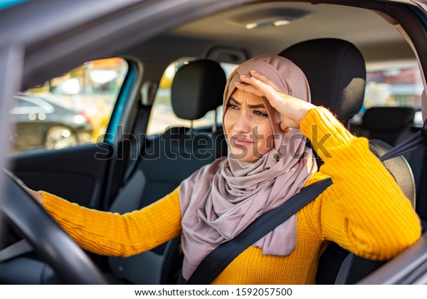 Stressed\
Muslim woman drive car feeling sad and angry. Distraught mid adult\
woman driving a car. Displeased young stressed angry pissed off\
woman driving car annoyed by heavy\
traffic