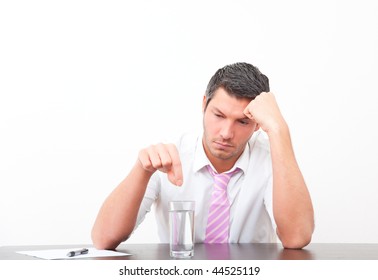 Stressed Office Man Putting Aspirin Head Ache Migraine Pill In Water Glass Sitting On Desk With Paper Document