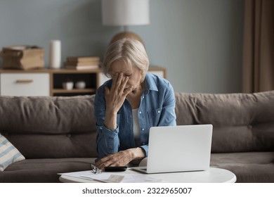 Stressed old woman sit on couch feels worried about money problem, suffer from lack of finances, check domestic expenditures, shocked about eviction notice. Financial crisis, insolvency, small pension - Powered by Shutterstock