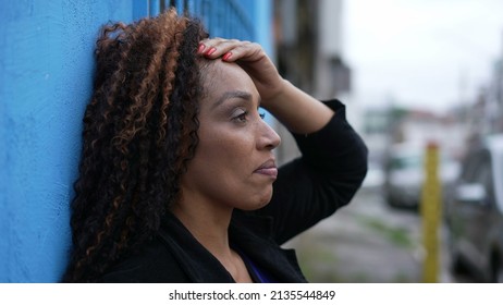 A Stressed Out African Woman Leaning On Wall Outside In Street