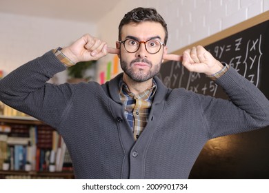 Stressed Out Teacher Blocking Ears In Classroom