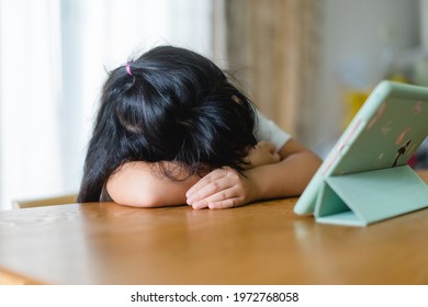 Stressed Out And Tired Asian Kids Girl Stay At Home And Learn From Home.Lazy Kid Girl Want To Go Back To School.No Online Learning.boring Face With Online Learning At Home.Education.sad Mental Health.