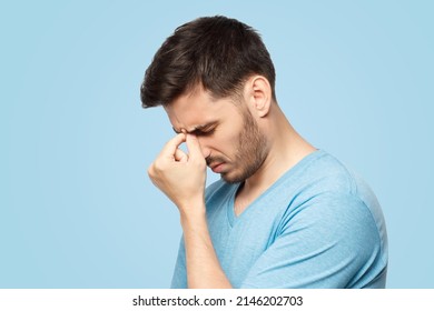 Stressed out young guy making facepalm gesture with hand, isolated on blue background