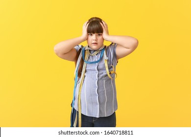 Stressed overweight girl with measuring tapes on color background