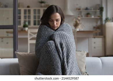 Stressed sad wrapped in plaid young woman feeling cold, ill, sick, suffering from fever, virus, trying to warm, sitting on couch at home. Frustrated shocked girl going through depression - Shutterstock ID 2144529587
