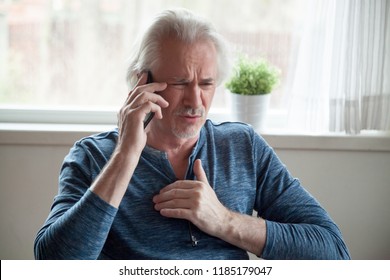 Stressed Senior Mature Man Feeling Pain Having Heart Attack Talking On Phone Hearing Bad News, Old Middle Aged Male Calling Emergency Touching Chest Suffer From Heartache Disease At Home, Infarction