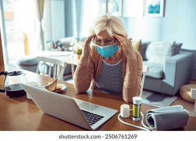 Stressed senior woman wearing face mask while checking health information online at home - Powered by Shutterstock