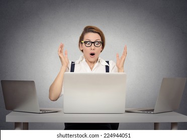 Stressed shocked businesswoman sitting at table in front of multiple computers in her office looking stunned wide open mouth. Negative human face expressions, emotion feeling body language reaction