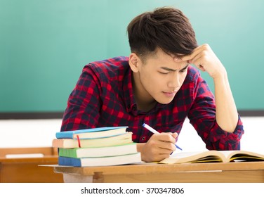 Stressed Student  Studying For Exam In Classroom