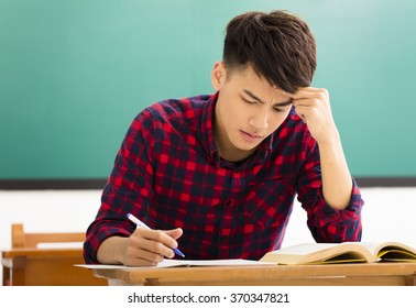 Stressed Student  Studying For Exam In Classroom