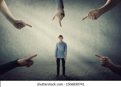 Stressed Teen Boy, Under Pressure, Looking Down Feel Ashamed And Discomfort As Lots Of Hands Pointing Index To Him Blaming As Guilty. Upset Student Experiencing Adolescence Crisis, Regret The Mistake.