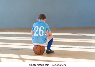 Stressed Tired Exhausted Child With Ball In A Physical Education Lesson. Safe Back To School During Pandemic Concept. Social Distancing To Fight COVID-19
