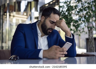 Stressed tired Moroccan businessman using mobile phone missed deadline, having headache sitting in office. Depression, overwork concept - Shutterstock ID 2142185595