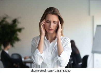 Stressed tired sad professional young business woman feeling sick headache at work standing in office, frustrated overworked female executive suffer from pain pressure migraine at workplace concept - Shutterstock ID 1486763960