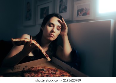 

Stressed Tired Woman Having A Slice Of Pizza At Night. Unhappy Tired Depressed Person Binge Eating During Nighttime
