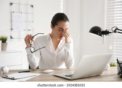 Stressed And Tired Young Woman With Headache At Workplace