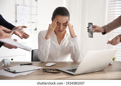 Stressed and tired young woman surrounded by colleagues at workplace, closeup