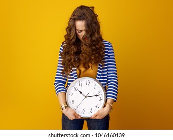 Stressed Trendy Woman In Striped Jacket Against Yellow Background With Clock