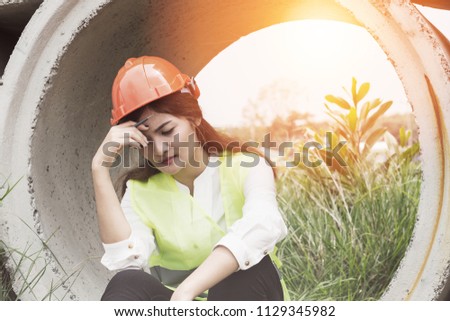 Stressed and tried of engineer Asian woman sitting on ground with white helmet after construction problem and lost job