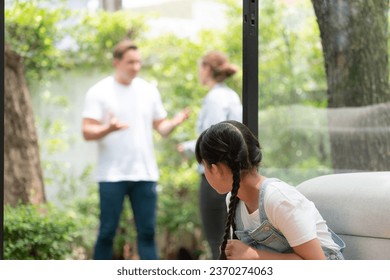 Stressed and unhappy young girl huddle in corner crying and sad while her parent arguing in background. Domestic violence at home and traumatic childhood develop to depression. Synchronos - Powered by Shutterstock