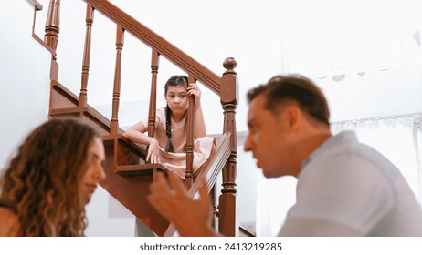 Stressed and unhappy young girl watch her parent arguing from the stair. Domestic violence at home and traumatic childhood develop to depression and anxiety. Unhealthy family concept. Synchronos - Powered by Shutterstock