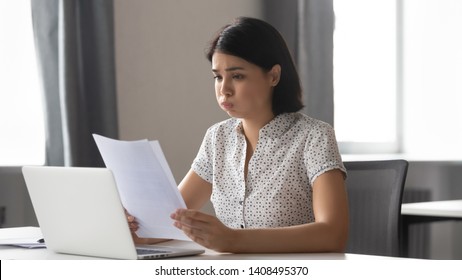 Stressed upset asian business woman student worker reading bad news in paper letter report feel frustrated about debt notification rejection failed test exam result sitting at office desk, got fired
