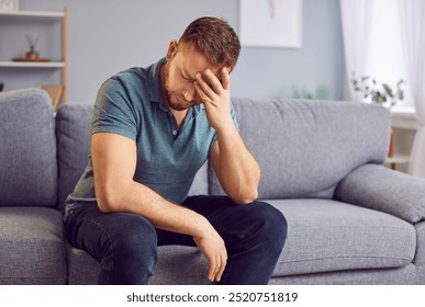 Stressed upset man sitting alone on a comfortable couch, appearing distraught, holding his head in hands, deep in thought or contemplation. Sad guy thinking about problems in relationships or at work - Powered by Shutterstock