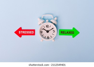 stressed vs relaxed. Red arrow and green arrow- direction indicator - choice of stressed or relaxed. Concept of choice. Two Arrows and clock on blue background, top view
