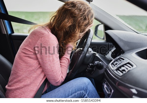 Stressed woman covering face with hands in car.\
Driver panic concept