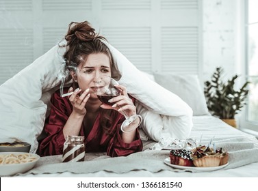 Stressed Woman. A Depressed Woman Smoking In The Bed And Drinking Wine